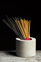 Many different aromatic incense sticks in grey vase.