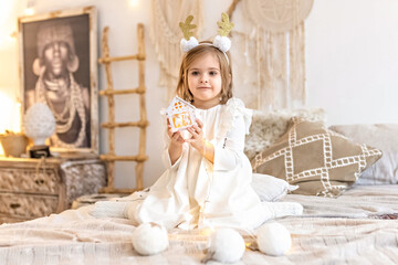 Portrait of a little girl Toddler with a headband on her head in the form of deer horns and a Christmas toy in her hands. Christmas holidays.Light and bright