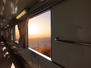 Walkway train interior with sunset mountain view outside.