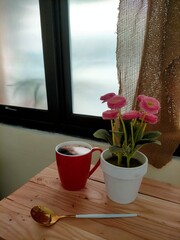 flower in the pot and coffee on window background 