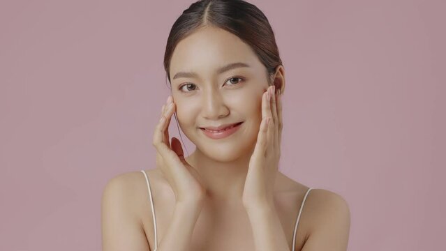 Slow motion close up perfect beauty face of young beautiful Asian woman massages her face gently with fingertips. Face cream commercial advertising concept.