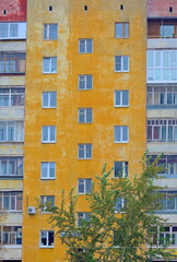 Fototapeta na wymiar Fragment of the facade of an old multi-storey residential building on an autumn day