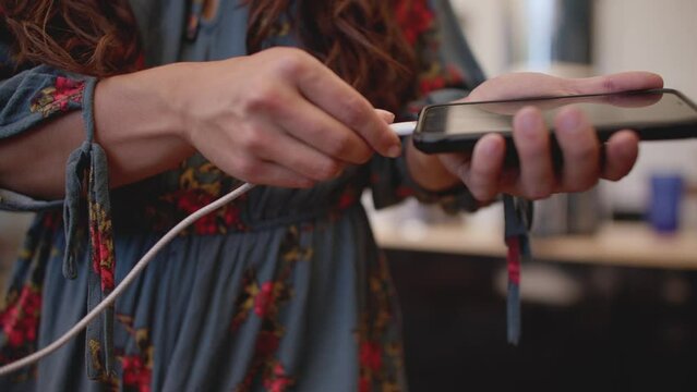 Close up, female hand plugging charger into phone