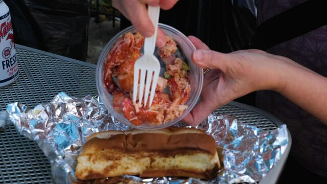 Loading lobster on a bun for a Lobster Rolls sandwich