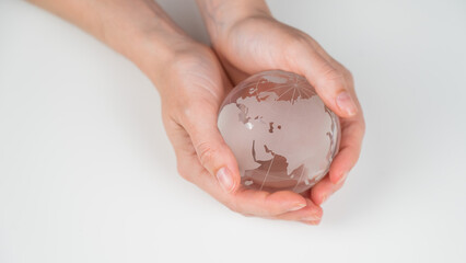 Crystal globe in female hands on a white background. 