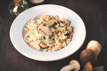 Risotto with mushrooms porcini (Boletus Edulis)
 on wooden dark rustic background. Healthy tradition nord Italian and French recipes, autumn and winter homemade cooking
