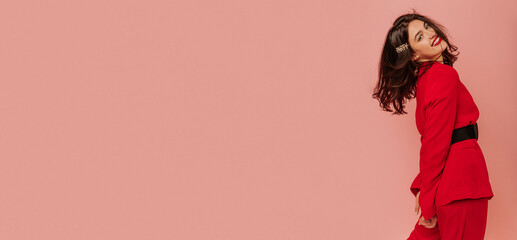 Stylish young caucasian brunette girl with wavy hair smiling with teeth on pink background. Model...