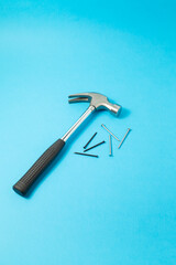 Steel hammer and nails on a blue background. Promotional photo of working tools.