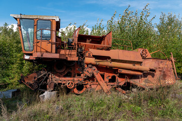 Old rusty agricultural machinery. Abandoned harvester, tractor