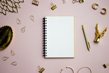 White notebook with golden pen, leave over the pink table.