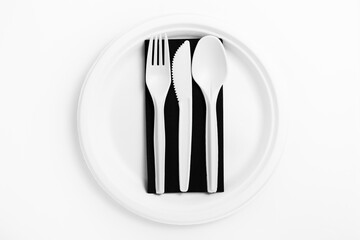 Biodegradable disposable white tableware: plate, napkin, fork with knife and spoon on a white background. Ecological trend, close-up.
