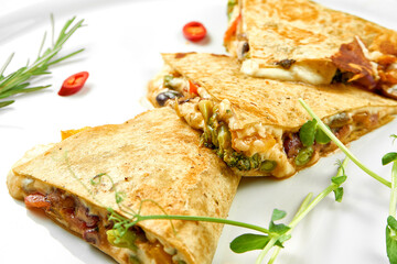 Quesadilla with cheese and vegetables in a white plate. Close-up, selective focus. White background.