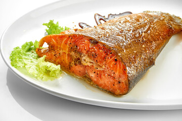 Grilled salmon tail in a white plate. White background. Selective focus. Close-up