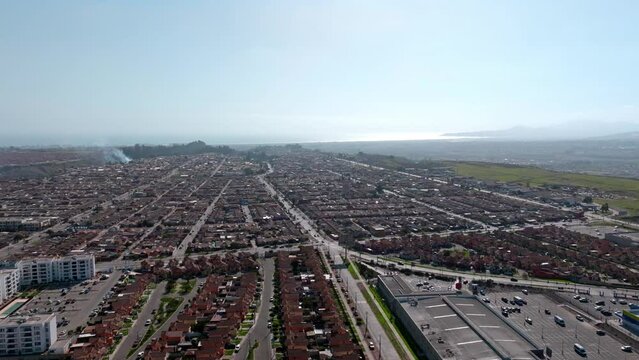 Aerial orbit of a town of small, tile-roofed houses on a sunny day.