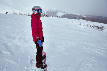 Fototapeta na wymiar Caucasian woman snowboarding on empty track of Carpathians, Ukraine ski resort on a beautiful sunny winter day