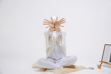 A girl in white clothes on a white background is doing yoga