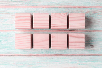 Eight blank pink wooden cubes on wooden plates