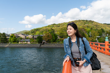 happy asian Japanese girl traveler enjoying breeze and natural beauty on uji bashi bridge over uji...