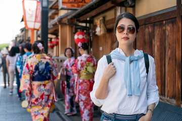 stylish asian chinese woman looking around Gion Hanamikoji Street in Kyoto japan with a group of girls wearing kimono traditional Japanese clothes at background - obrazy, fototapety, plakaty
