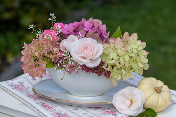 florales Arrangement mit weißer Rose und Hortensien-Blüten in vintage Sauciere