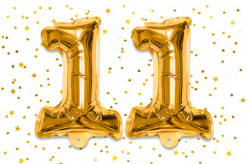 The number of the balloon made of golden foil, the number eleven on a white background with sequins. Birthday greeting card with inscription 11. Numerical digit, Celebration event.