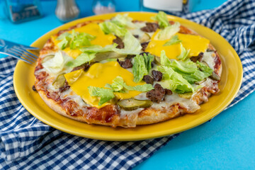 Pizza hamburger with meat shashlik, mustard, lettuce, cheese, sauce. Food in a yellow plate on a blue background. Menu. Homemade pastries. Meal with meat. Food on the table.