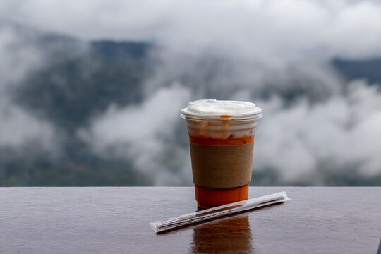 Close up photo of iced milk tea in plastic glass on table and blurred nature background.