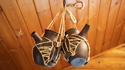 Two earthenware jars with spouts are suspended on a rope. Ceramic tableware.