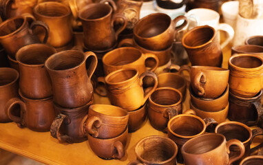 A collection of earthenware, many mugs and jugs on the table. Background