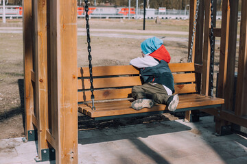 The offended boy is sitting on a lifestyle bench . Childish grievances. Childish anger. An article...
