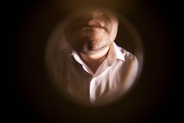 View from the peephole. A man in a white shirt is standing near the front door. The concept of...