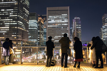 KITTE丸の内からビル群の夜景を観る人々　東京駅　People enjoying night view of Marunouchi District from rooftop garden of Kitte near Tokyo Railway Station