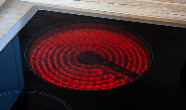 Incandescent burner of an induction hob in the kitchen, close-up. Black ceramic hob, modern stove