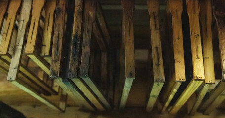 Bee frames with sealed combs and honey hang in the shed. Breeding bees, beekeeping, honey extraction, indusrty