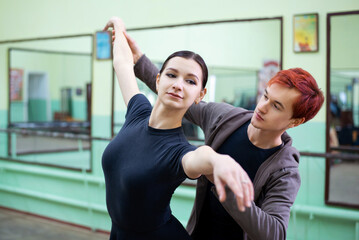 Fototapeta na wymiar Male dance tutor helps ballerina to learn new moves and perform them correctly. Dance teacher, learning choreography