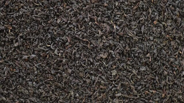 Black dry Tea Wallpaper. Black Tea Leaves rotating on Turntable. Close Up, Macro. Top View. Slow Motion. Texture. Full Frame. Copy Space. Dried Tea is Spinning. Dark Abstract Food and Drink Background
