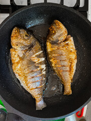 Fresh raw dorado fish or sea bream with in a dark frying pan. Mediterranean Kitchen. Top view Healthy and diet food concept.