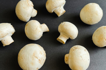 Fresh champignon mushrooms are laid out on a black background.