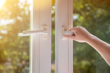 woman hand open white plastic window at home. The concept of ventilation.
