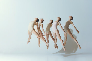 Group of young girls, ballet dancers performing, posing isolated over grey studio background. Jumping