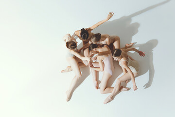 Group of young girls, ballet dancers performing, posing isolated over grey studio background. Art of classics