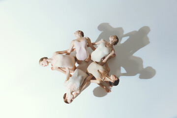 Group of young girls, ballet dancers performing, posing isolated over grey studio background. Blooming flower. Top view