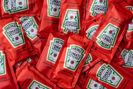 Packets of single serving Heinz Tomato Ketchup on wooden background.