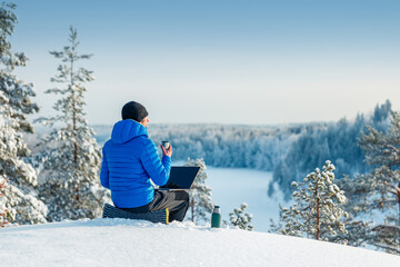 Winter freelance. Man with laptop and thermos working outdoor in winter.