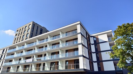 Fototapeta premium Modern residential building with new apartments in a green residential area. Eco architecture. Green tree and new apartment building. The harmony of nature and modernity.