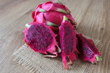 Red dragon fruit on burlap on wooden table. 