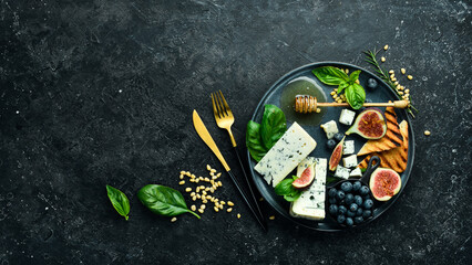 Blue cheese, figs, blueberries and honey on a plate. On a concrete background. Top view.
