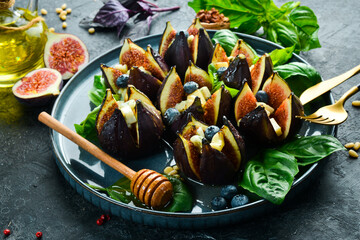 Homemade baked figs with blue cheese, honey and nuts. In a black bowl. Top view.