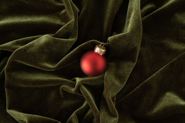 Red Christmas bauble on soft green velvet background.