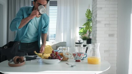 Young man hurrying up to work, taking breakfast.